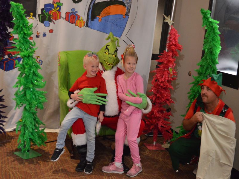 Kids pose with the Grinch at a photo opportunity location during the Whoville Holiday special event for Festival of Trees.