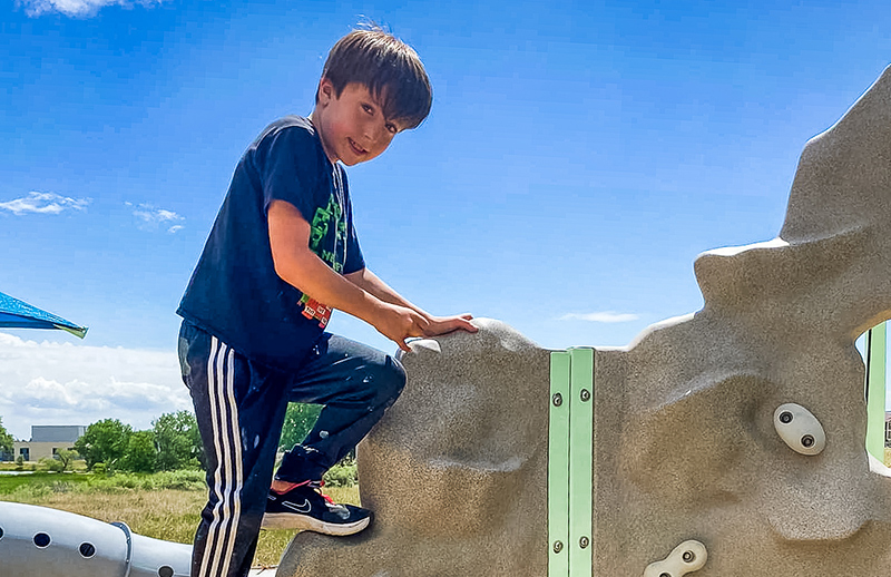 Young boy climbing on new playground equipment