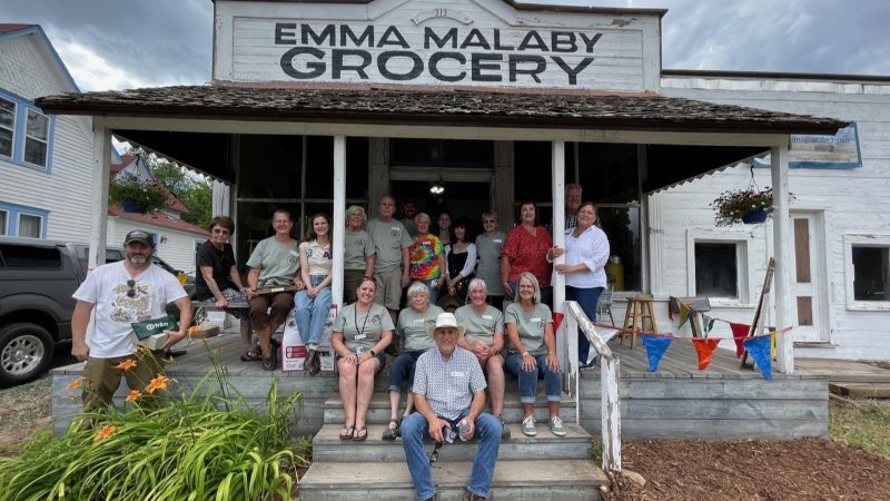 A group of people stand on the front porch of the Emma Malaby Grocery in Fort Collins.