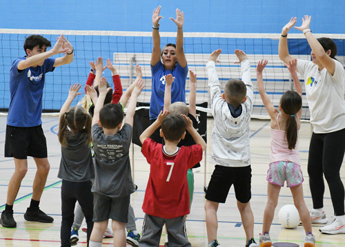 Greeley Rec staff teaching a group of kids to play volleyball.