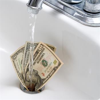 Money Down the Drain Dollar bills in drain.