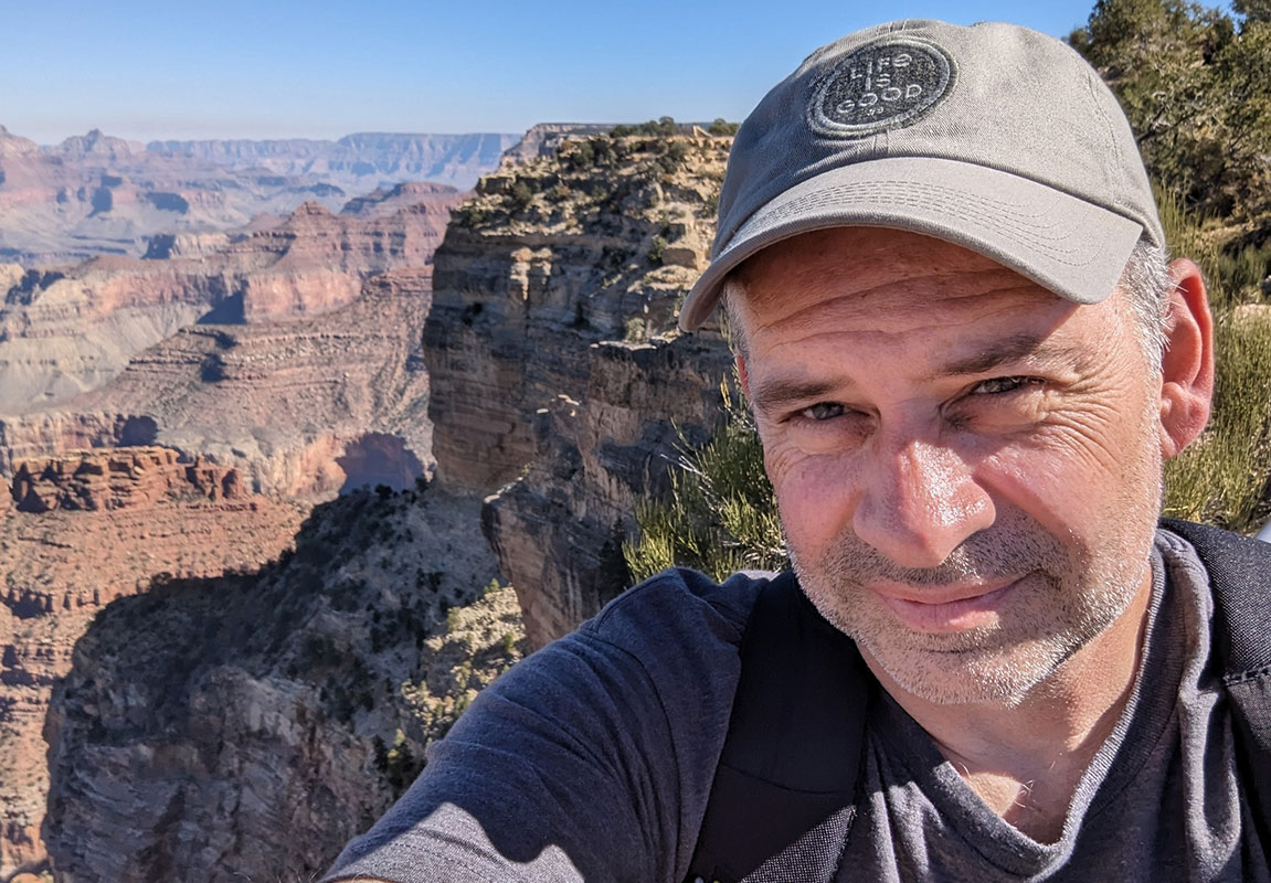Author John Daly in front of a canyon on a bright sunny day