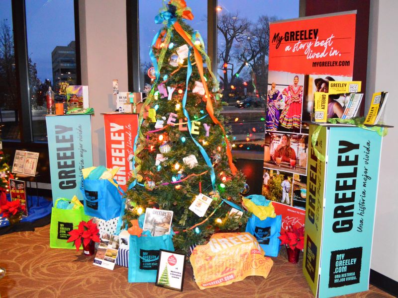 A Festival of Trees display in the Union Colony Civic Center lobby, featuring the My Greeley image campaign represented in signage, Greeley merchandise, and a colorfully decorated tree.