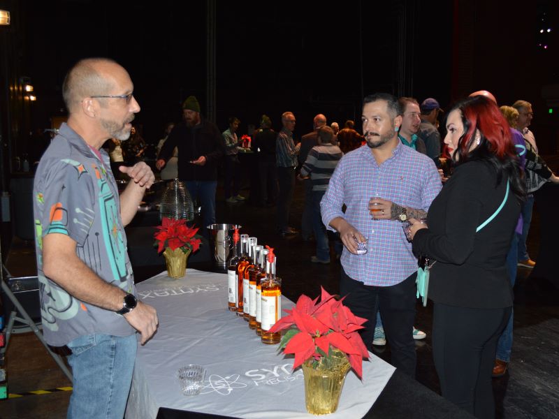 A vendor talking with two participants of the Whiskey and Wonderland special event for Festival of Trees.