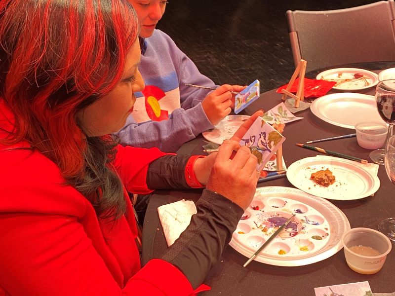 Participants of the Festival of Trees special event, Watercolor and Wine, paint winter birds on small canvases on the Monfort Concert Hall stage.