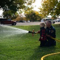 Firefighter training a young cadet with a fire hose
