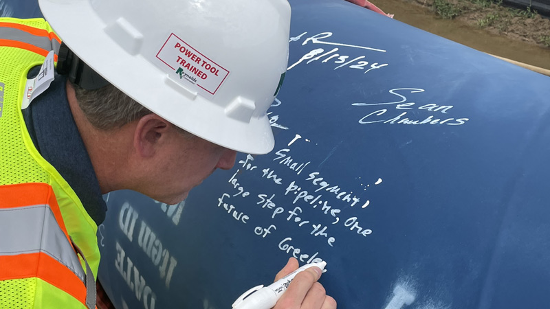 Adam Prior, chief engineer with Greeley’s Water and Sewer Department, inscribes a note on a section of the Terry Ranch pipeline to signify the project’s Phase 1 completion